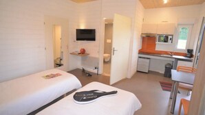 Et lille hotelværelse med to senge, fjernsyn, tekøkken og badeværelse.