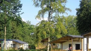 A row of cabins with wooden decks and a grassy area in front.