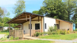 A single-story building with a covered porch, a small attached structure, and a gravel driveway.