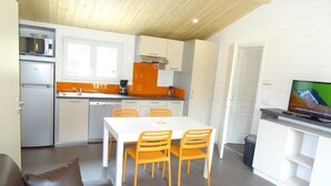 A compact living space with a kitchenette, dining area, and a television. - ZEcamping 3 étoiles animé piscine chauffée dog friendly hammam locatif TV LV (Merdrignac)