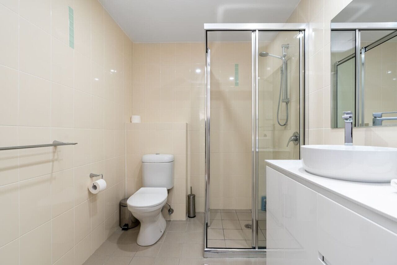Un baño moderno con inodoro, cabina de ducha de vidrio y lavabo con espejo.