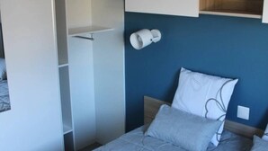 Une chambre à coucher avec un lit, une armoire et une table de chevet.