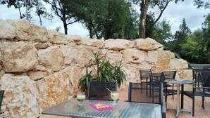 Eine Terrasse im Freien mit Steinmauern, Metalltischen und -stühlen.