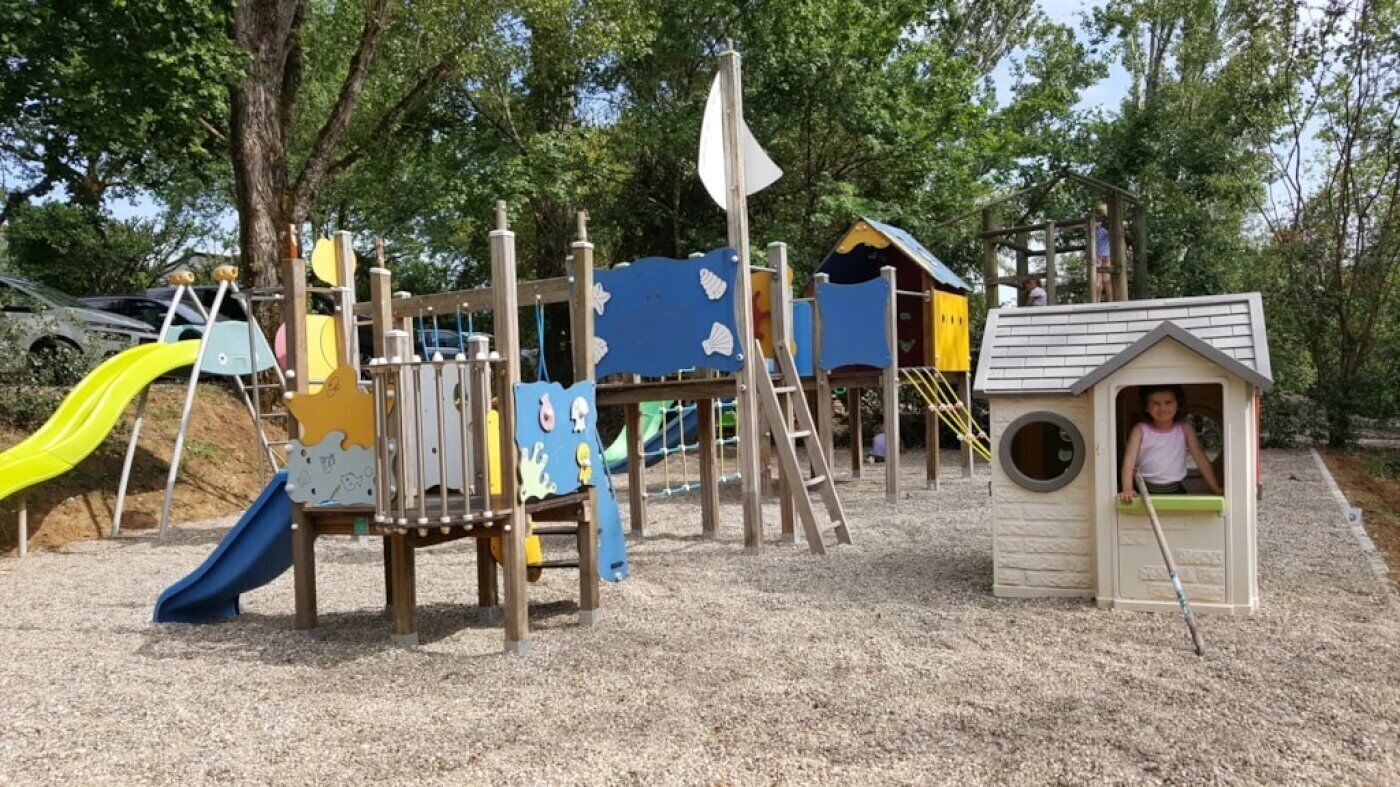 A playground with slides, climbing structures, and a small playhouse.