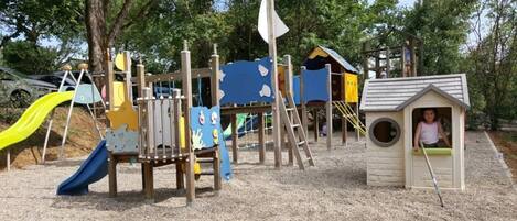 A playground with slides, climbing structures, and a small playhouse.