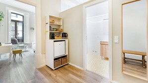 A compact living space with a kitchenette, a dining area, and a view through a glass door. - GuestReady - Alegria 293 - Room 1 (Porto)