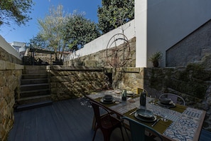 An outdoor dining area with a stone wall, a metal table, and chairs.