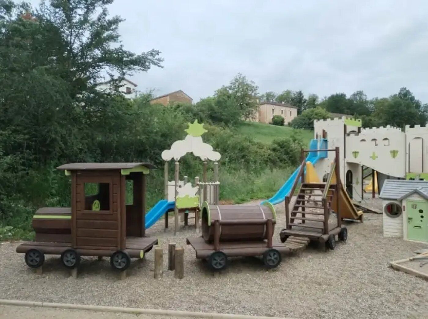 A children's play area with a train-themed play structure, including a slide and climbing elements.
