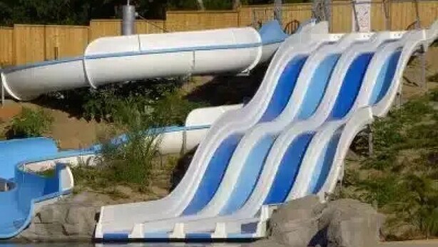 Ein Wasserpark mit einer blauen und weißen Rutsche und einem Schwimmbecken.