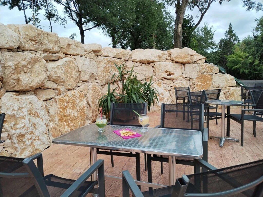 An outdoor patio with stone walls, metal tables, and chairs.