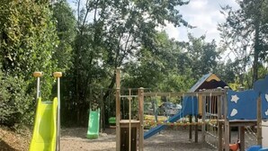 Un parque infantil con toboganes y estructuras para escalar, rodeado de árboles.