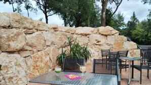 Un patio al aire libre con paredes de piedra, mesas y sillas de metal.