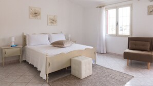 A bedroom with a bed, bedside tables, a chair, and artwork on the wall. - Casa Duesse (IUN R6224)Accommodation located in the very center of Orosei. (Orosei)