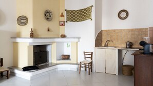 A kitchen with a built-in stove, a sink, and a small dining area with a chair. - Casa Duesse (IUN R6224)Accommodation located in the very center of Orosei. (Orosei)