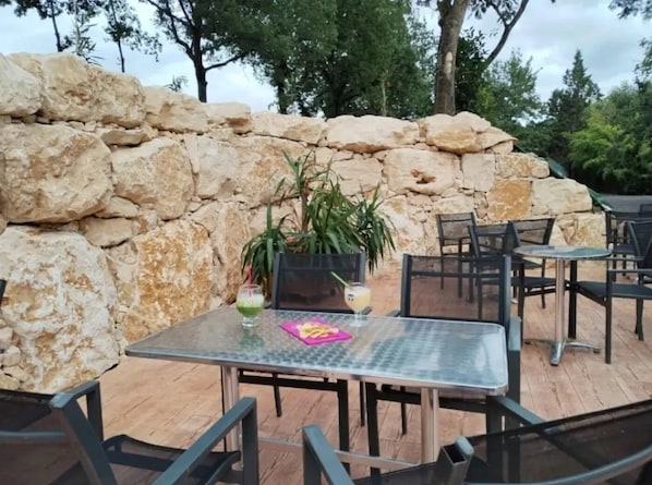 An outdoor patio with stone walls, metal tables, and chairs.
