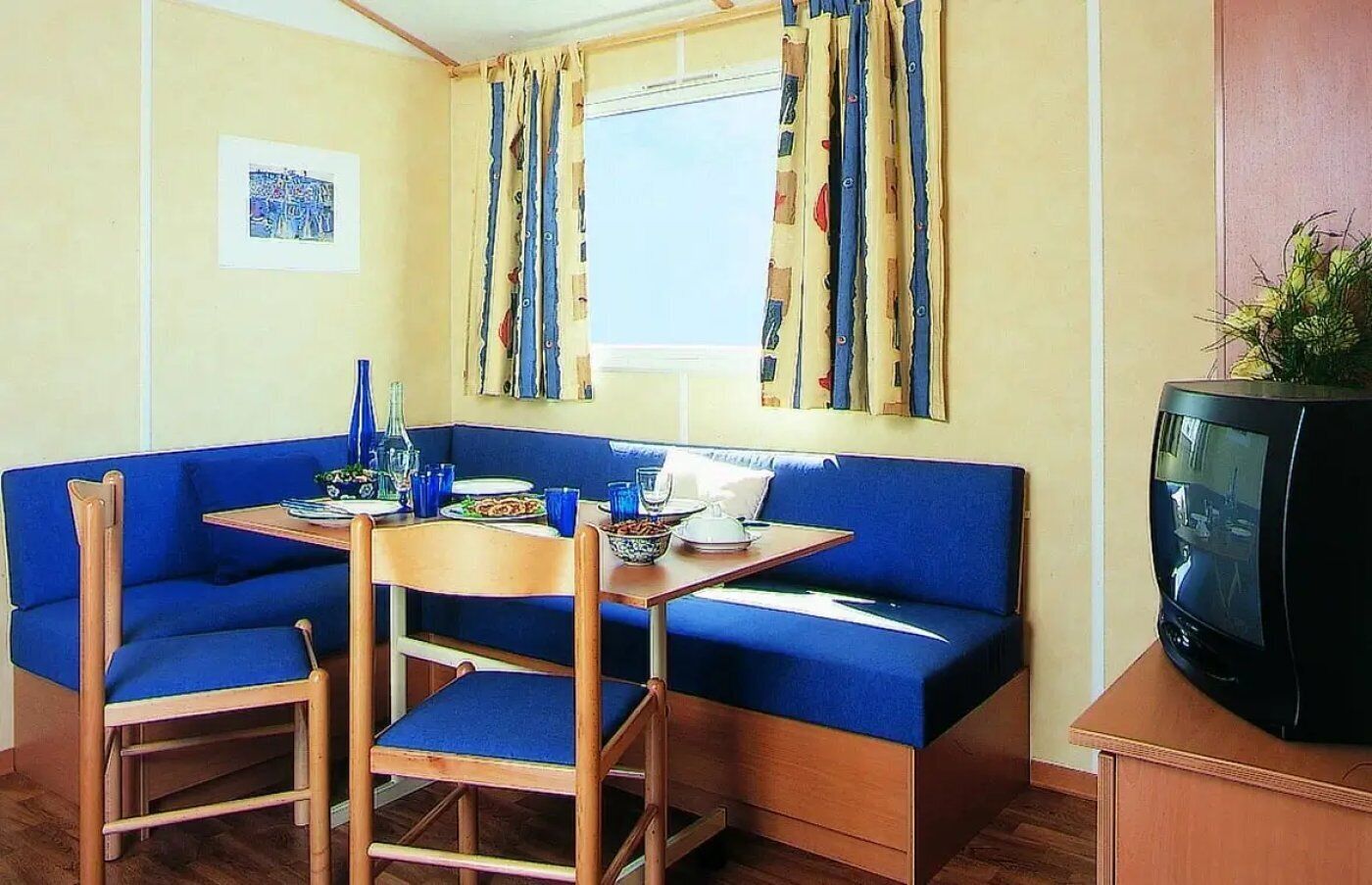 A compact room with a blue sofa, a wooden table, and a television.