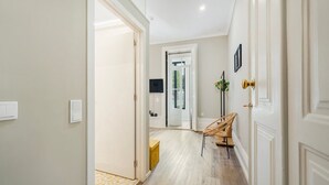 A hallway with a wooden floor, white walls, and a door leading to another room. - GuestReady - Alegria 293 - Room 2 (Porto)