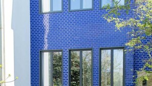 A modern building with a blue-tiled exterior, a swimming pool, and a stone staircase leading to the entrance. - GuestReady - Alegria 293 - Room 2 (Porto)