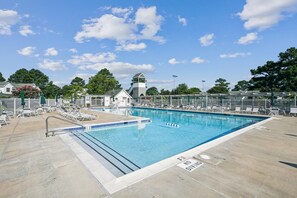 Une piscine dotée d’un poste de surveillance pour les sauveteurs, de chaises longues et d’une zone délimitée par une clôture.