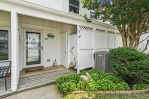 Un immeuble résidentiel doté d’une porte d’entrée, d’une boîte aux lettres et d’un petit jardin agrémenté d’un arbre et d’arbustes.