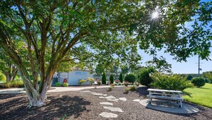 Un área de parque con un sendero de piedra, un banco y un letrero para la piscina.