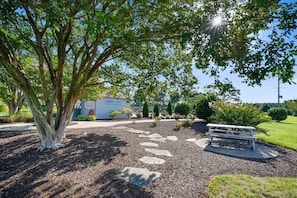 A park area with a stone path, a bench, and a sign for a pool. - Townhome with community pool, tennis court, and only 2 miles from Bethany Beach! (Frankford)