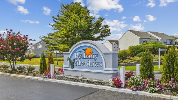Señal de Bethany Meadows, cielo despejado y casas residenciales al fondo.