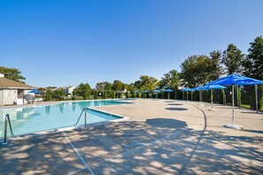 A swimming pool with a surrounding deck, shaded by trees and umbrellas. - Townhome with community pool, tennis court, and only 2 miles from Bethany Beach! (Frankford)