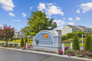 A sign for Bethany Meadows with a clear sky and residential buildings in the background. - Townhome with community pool, tennis court, and only 2 miles from Bethany Beach! (Frankford)