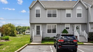 A two-story residential building with a front entrance, a driveway, and a parked vehicle. - Townhome with community pool, tennis court, and only 2 miles from Bethany Beach! (Frankford)