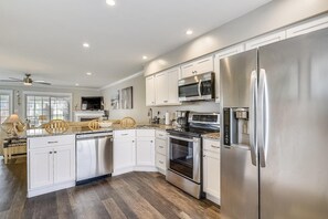 A modern kitchen with stainless steel appliances, white cabinetry, and a wooden dining area. - Townhome with community pool, tennis court, and only 2 miles from Bethany Beach! (Frankford)