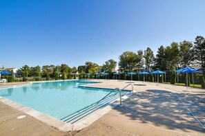 A clear blue swimming pool with a diving board, surrounded by a fence and shaded by blue umbrellas. - Townhome with community pool, tennis court, and only 2 miles from Bethany Beach! (Frankford)