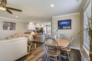 A modern kitchen with white cabinets, a microwave, and a refrigerator. There is a dining area with a wooden table and metal chairs. - Townhome with community pool, tennis court, and only 2 miles from Bethany Beach! (Frankford)