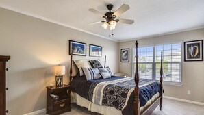 A bedroom with a four-poster bed, a nightstand with a lamp, a ceiling fan, and framed artwork on the walls. - Townhome with community pool, tennis court, and only 2 miles from Bethany Beach! (Frankford)