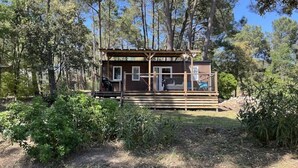 Eine Holzhütte mit einer Holzterrasse, umgeben von Bäumen.