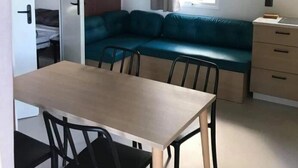 Ein gemütlicher Wohnbereich mit Esstisch, Stühlen, einer Couch und einer Küchenzeile.