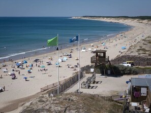 A beach with tents, a lifeguard tower, and a wooden fence.