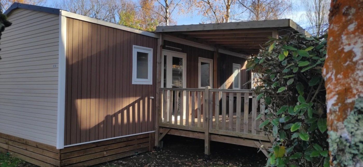 Una piccola casa mobile a un piano con una veranda in legno e un portico coperto.