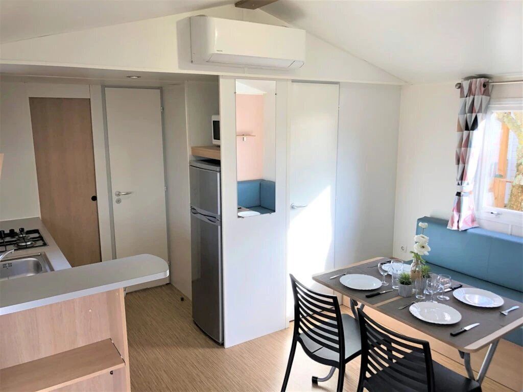 A compact kitchen with a stove, refrigerator, and a dining area with a table set for two.