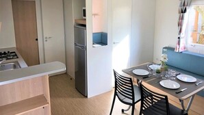 Una cocina compacta con estufa, refrigerador y comedor con una mesa dispuesta para dos.