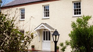 A traditional building with a white door, multiple windows, and a small porch.
