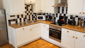 A kitchen with white cabinets, a microwave, a stove, and a sink.