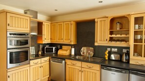 Une cuisine moderne avec des meubles en bois, des appareils en acier inoxydable et un plan de travail noir.