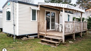 Une maison mobile dotée d’une terrasse en bois, d’un porche couvert et d’une porte-fenêtre coulissante.