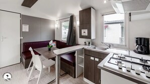 Une petite cuisine équipée avec une cuisinière à gaz, un évier et un coin repas comprenant une table et des chaises.