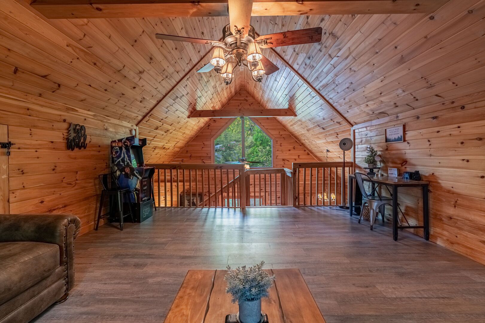 A spacious loft with wooden walls, a high ceiling, and a central wooden staircase.