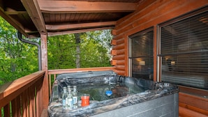 Un jacuzzi en una terraza de madera con vistas a árboles.