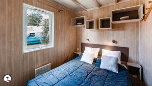 Un dormitorio con una cama grande, una ventana que da a un vehículo azul y estanterías empotradas.