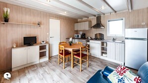 Una cocina moderna con armarios de madera, un comedor con mesa y sillas de madera, y un televisor integrado.
