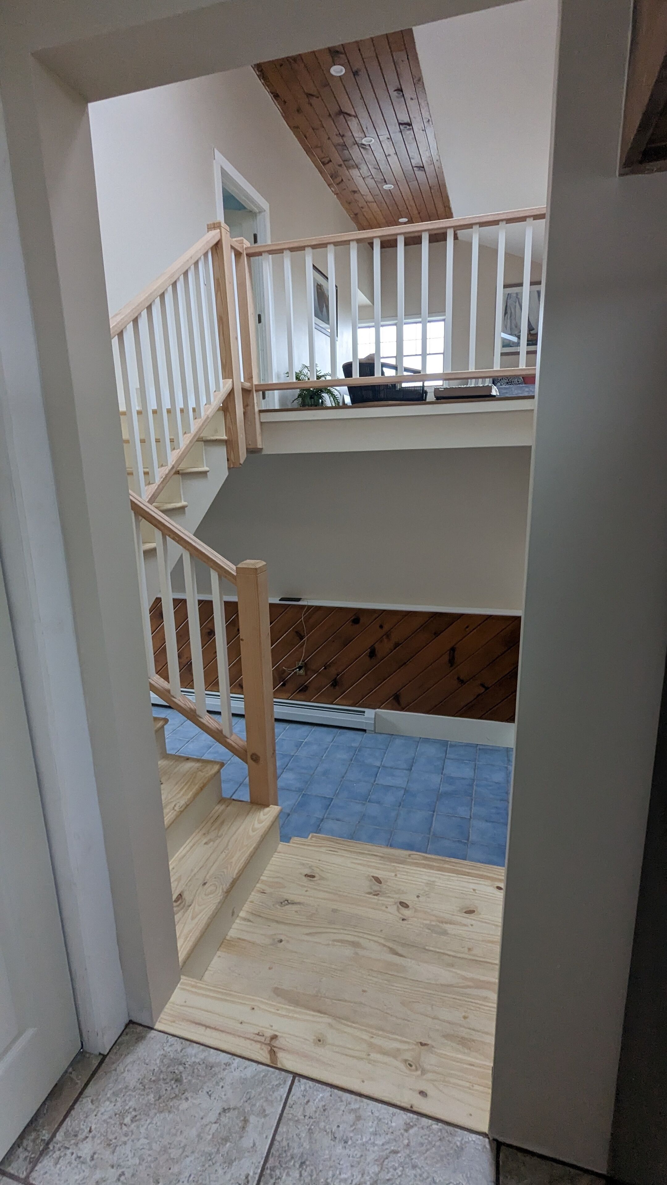 Un escalier menant à un deuxième étage, avec un plafond en bois et une vue sur l’étage supérieur.